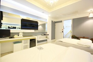 A modern hotel room with a bed, a desk with a flat-screen TV, a minibar, and a small seating area. - Dom Hotel (Gwangju)