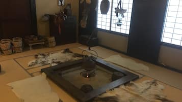 A traditional tatami mat room with a central heating stove, a window with a view, and various decorative items.