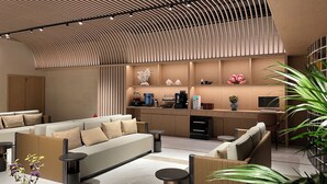 Un espace de détente moderne comprenant un canapé, un coin café et une grande plante.