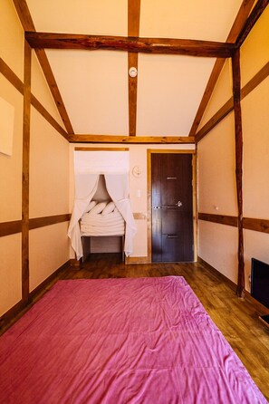 A bedroom with a wooden ceiling, a bed with a pink bedspread, a white canopy, and a wooden door. - Hohomom Guesthouse (Jeonju)
