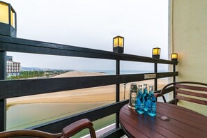 A balcony with a view of the beach, a table with bottles, and two wall-mounted lanterns. - Elmar Condotel (Yangyang)