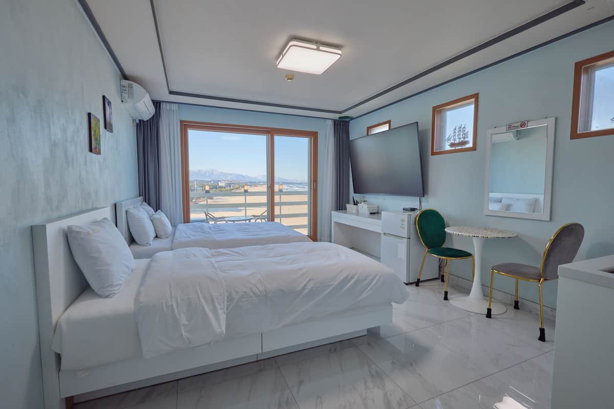 A modern hotel room with a large bed, a desk, a chair, and a TV.