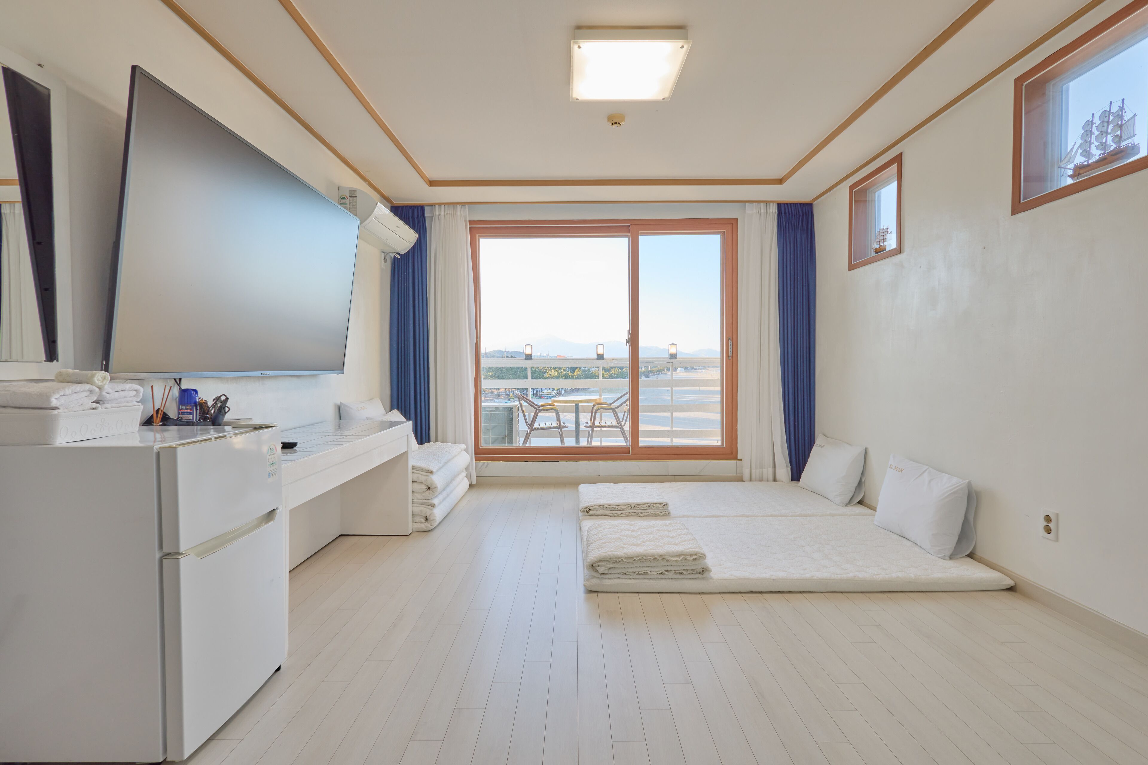 A hotel room with a bed, a desk, a large window, and a view of the city.