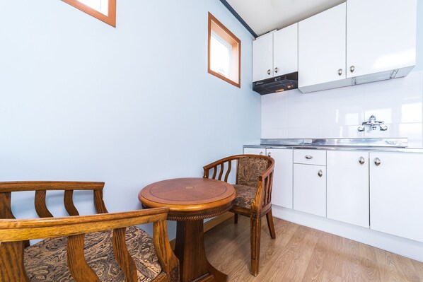 A compact kitchen with white cabinets, a built-in stove, and a small dining table with two chairs.