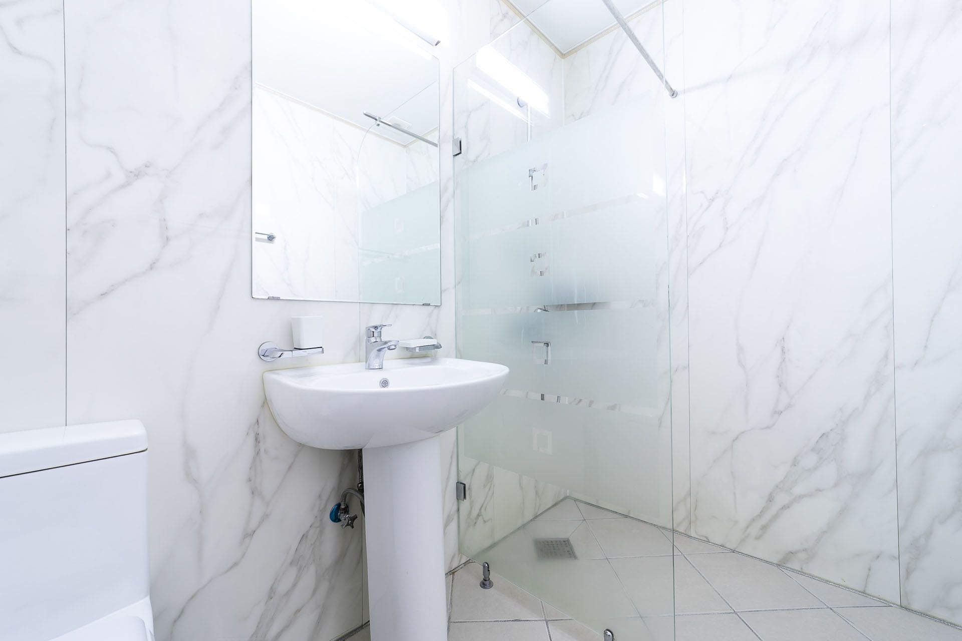 A bathroom with a white sink, mirror, and glass shower enclosure.