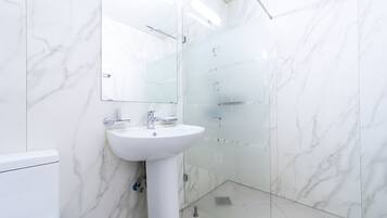 A bathroom with a white sink, mirror, and glass shower enclosure.