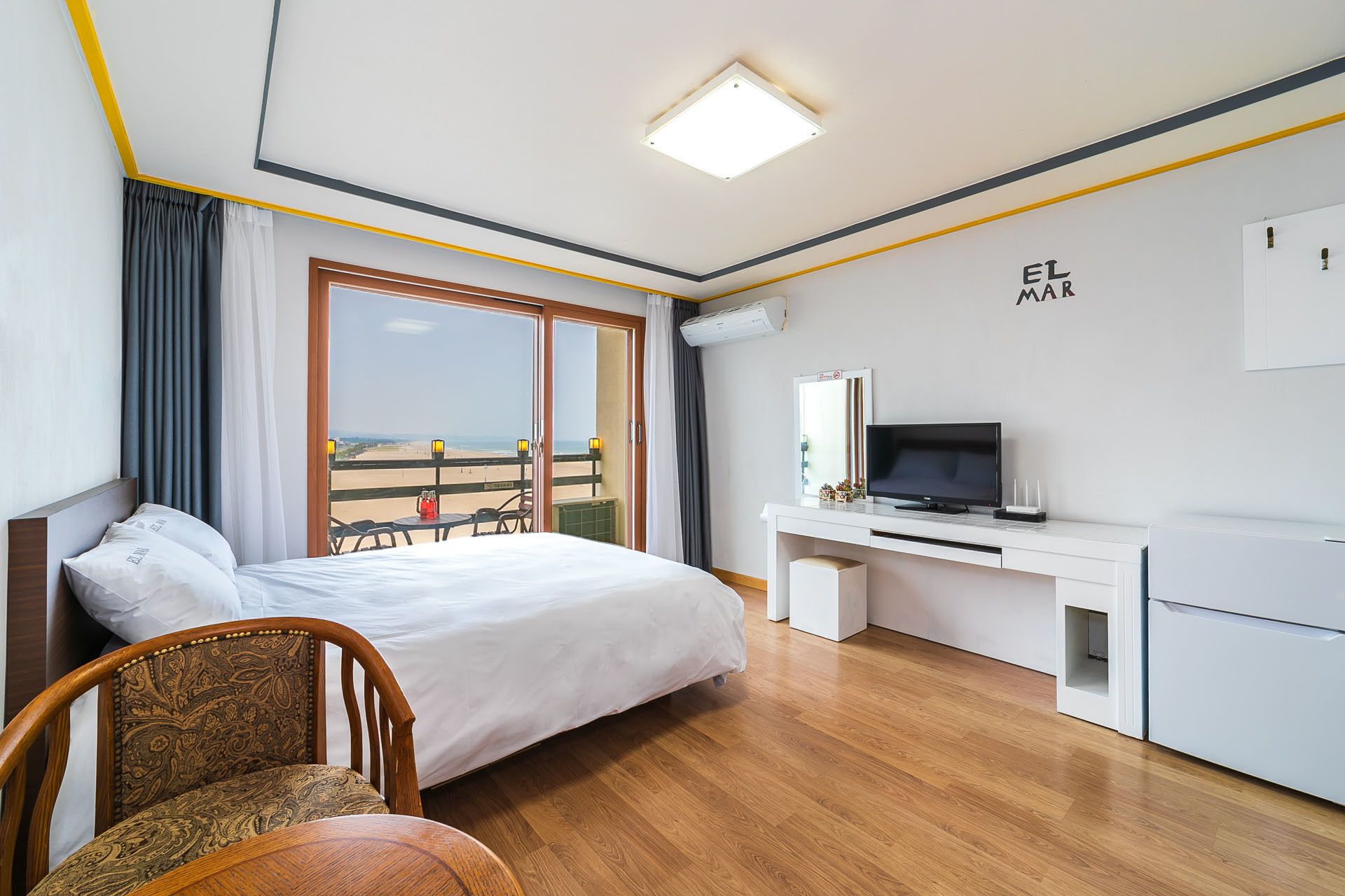 Een hotelkamer met een bed, een bureau met een televisie, een stoel en een balkon met uitzicht.