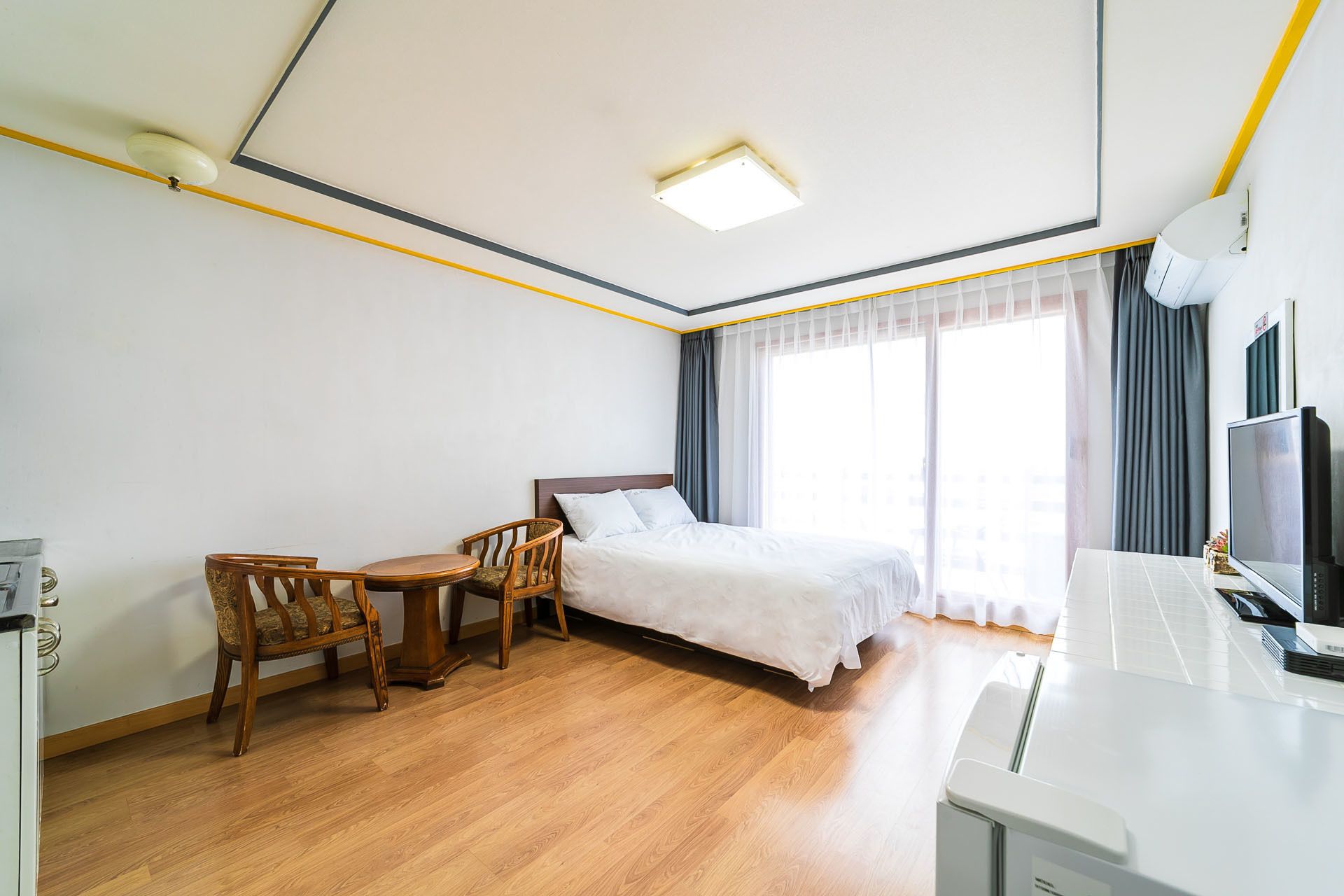 Una habitación de hotel con cama, escritorio, silla, televisión y lámpara de escritorio.