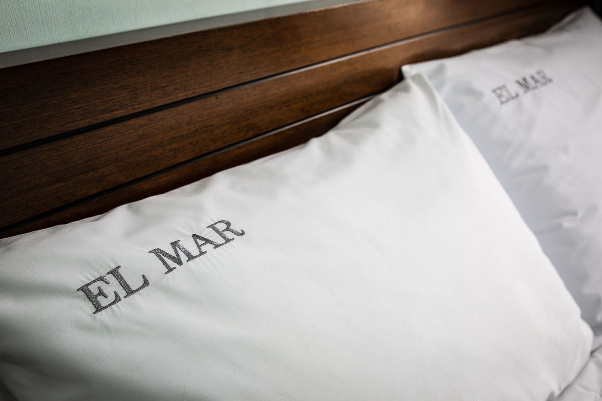 A bed with white pillows labeled "EL MAR".