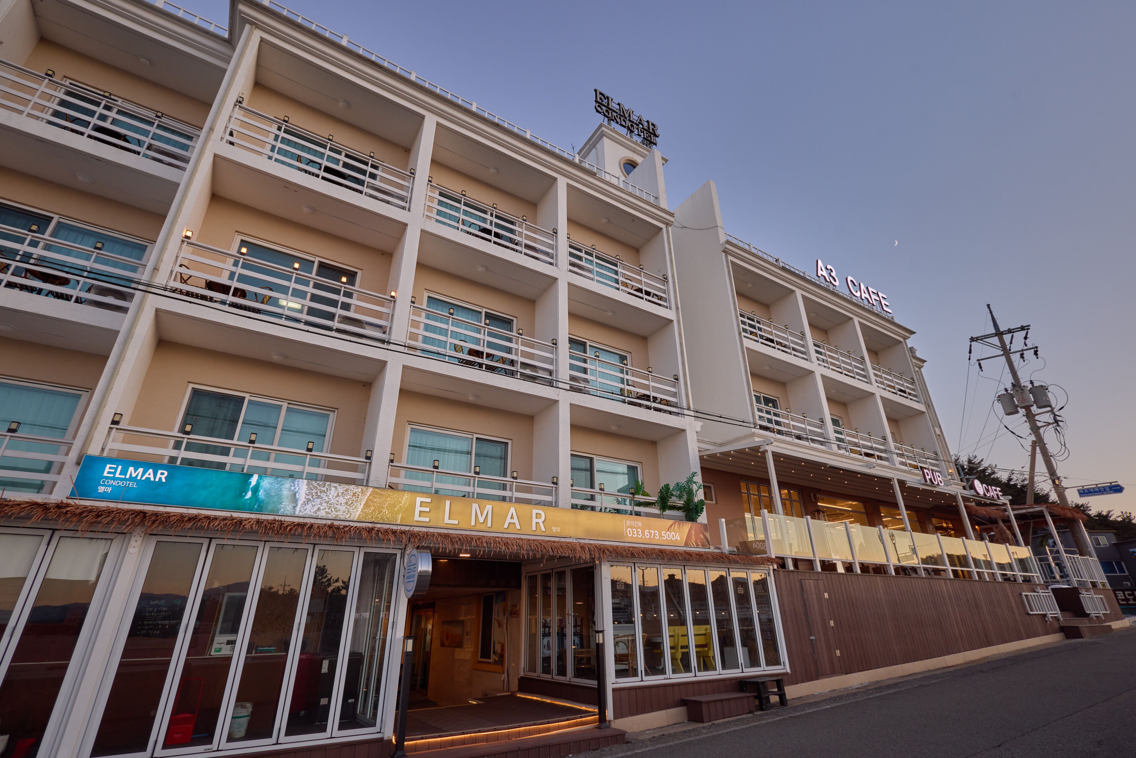 A multi-story hotel with balconies, a cafe, and a visible outdoor seating area.