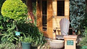 Ein Spa-Bereich für die Füße aus Holz mit einem Schild, einem Stuhl und Blumentöpfen.