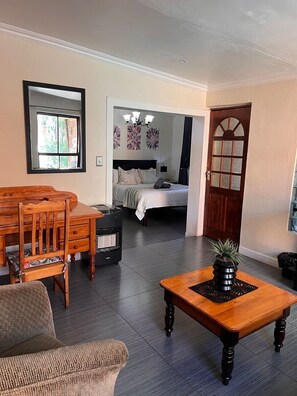Una habitación con una mesa de comedor, sillas, un sofá, una cama, un calefactor y una planta en maceta.