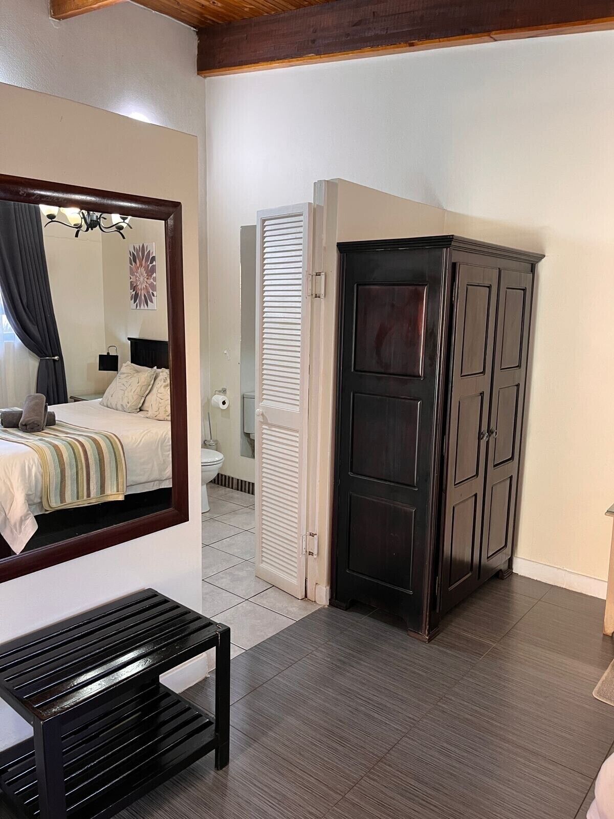 A bedroom with a bed, a bedside table, a wardrobe, and a mirror.