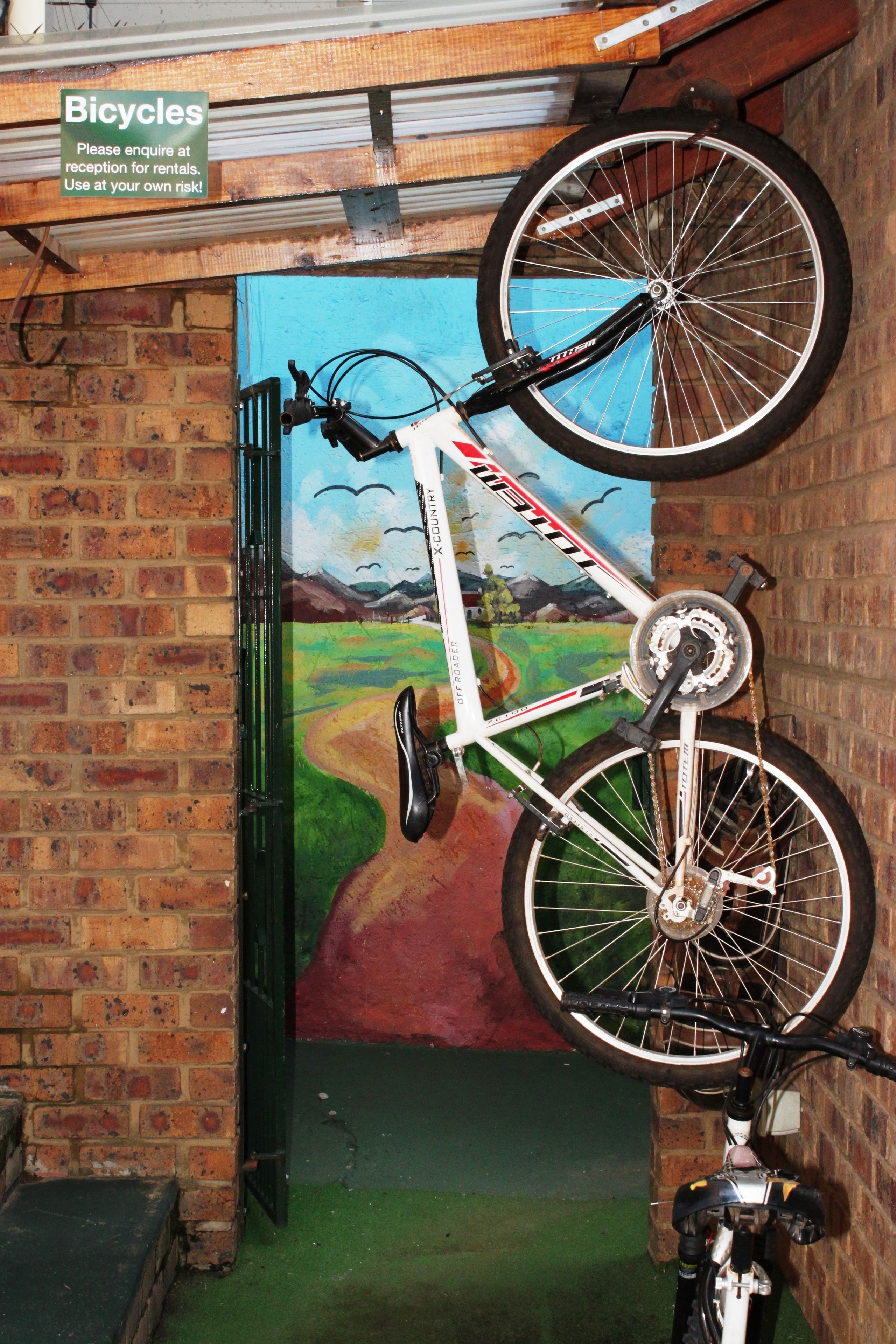 Una bicicleta apoyada en un muro de ladrillo con un mural de un paisaje.