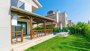 A modern residential building with a covered patio area, a well-maintained lawn, and a clear sky. - Paradise Town Villa Lisa (Serik)