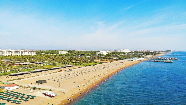 A beach with rows of umbrellas and a boat docked near the shore. - Paradise Town Villa Lisa (Serik)