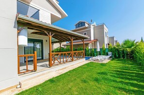 A modern residential building with a covered patio area, a well-maintained lawn, and a clear sky. - Paradise Town Villa Lisa (Serik)