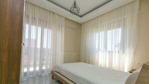 A bedroom with a bed, curtains, and a ceiling light. - Paradise Town Villa Lisa (Serik)