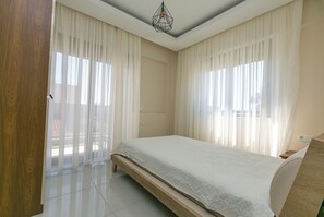 Een slaapkamer met een bed, gordijnen en een plafondlamp.