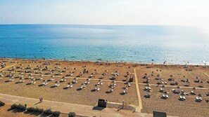 An aerial view of a beach with rows of sun loungers and umbrellas, a lifeguard tower, and the sea in the background. - Paradise Town Villa Lisa (Serik)