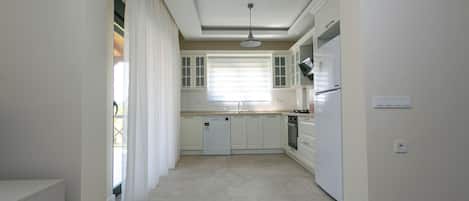 Una cocina moderna con armarios blancos, lavavajillas y refrigerador.