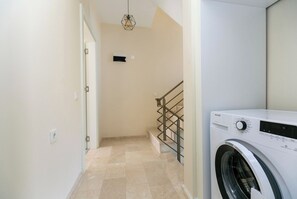 A laundry room with a washing machine, a staircase, and a light fixture. - Paradise Town Villa Lisa (Serik)