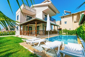 A modern two-story house with a swimming pool, a covered patio with lounge chairs, and a well-maintained lawn. - Paradise Town Villa Lisa (Serik)