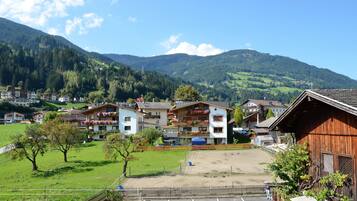 Un pueblo de montaña con casas de madera tradicionales, un área de estacionamiento y vistas de las colinas circundantes.