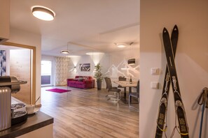 A modern living room with a red sofa, a dining table, and a coffee machine. - Aparthotel AlpTirol (Kaltenbach)