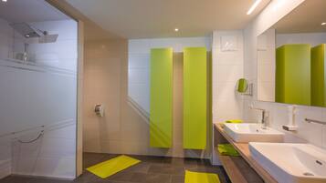 Un baño moderno con cabina de ducha de vidrio, dos lavamanos y un espejo.