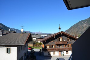 A traditional chalet with a sloped roof, wooden balconies, and a mountain backdrop.