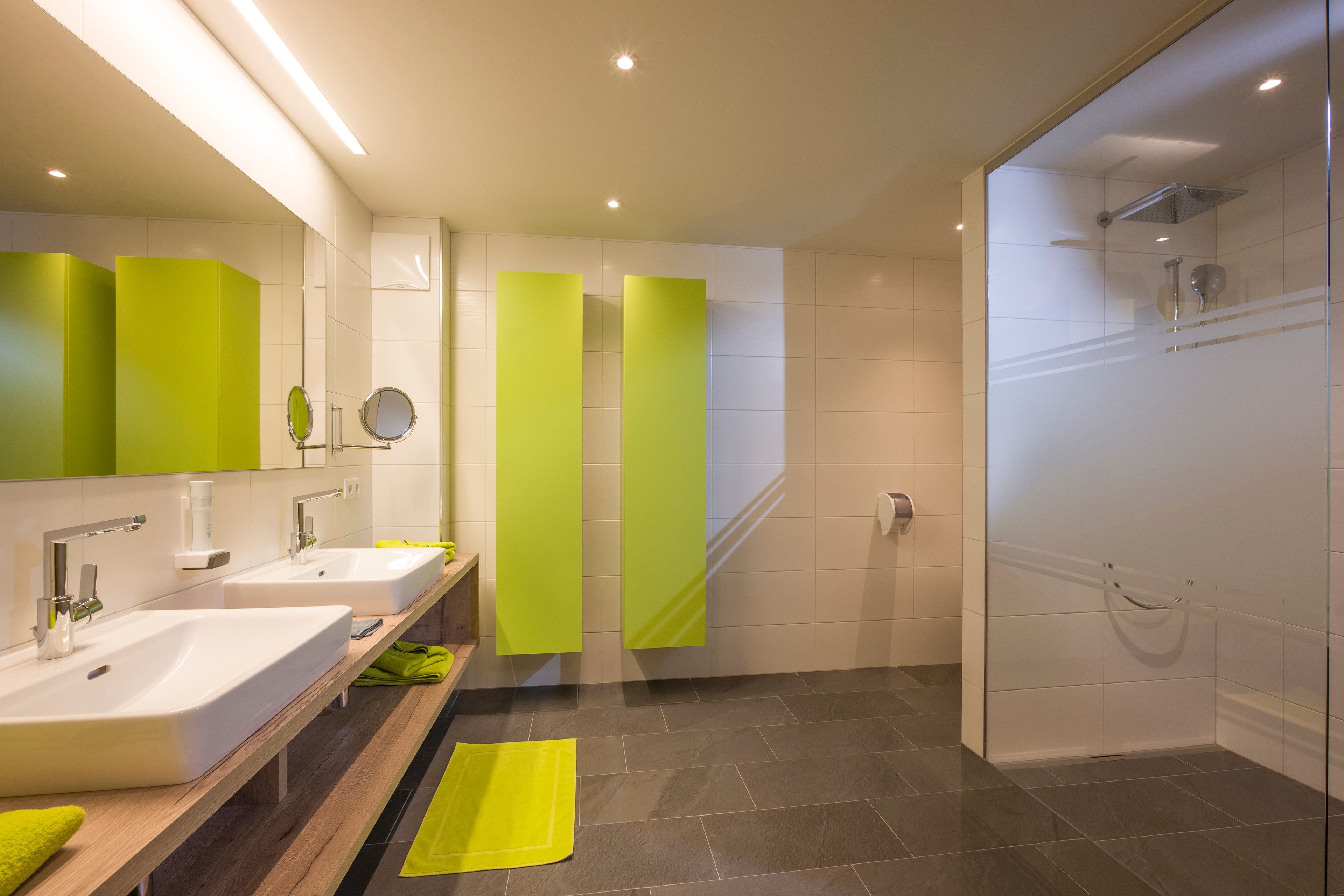Een moderne badkamer met twee wastafels, een douche en een douchecabine met glazen wanden.