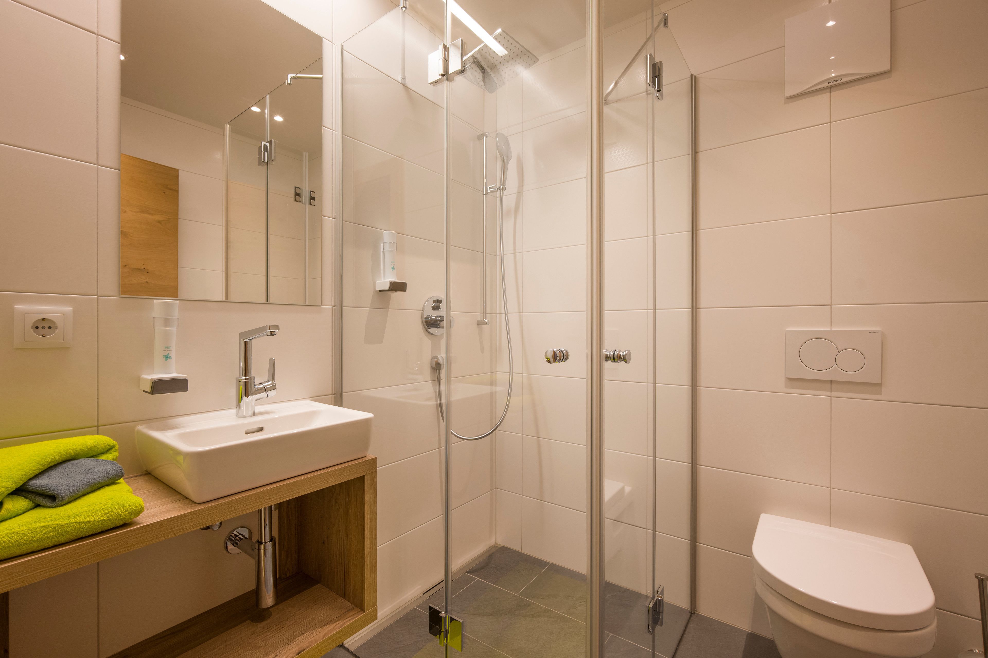 Une salle de bain moderne avec une douche à parois de verre, un lavabo blanc et des toilettes.
