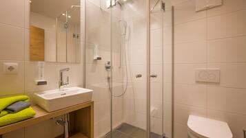 Une salle de bain moderne avec une douche à parois de verre, un lavabo blanc et des toilettes.