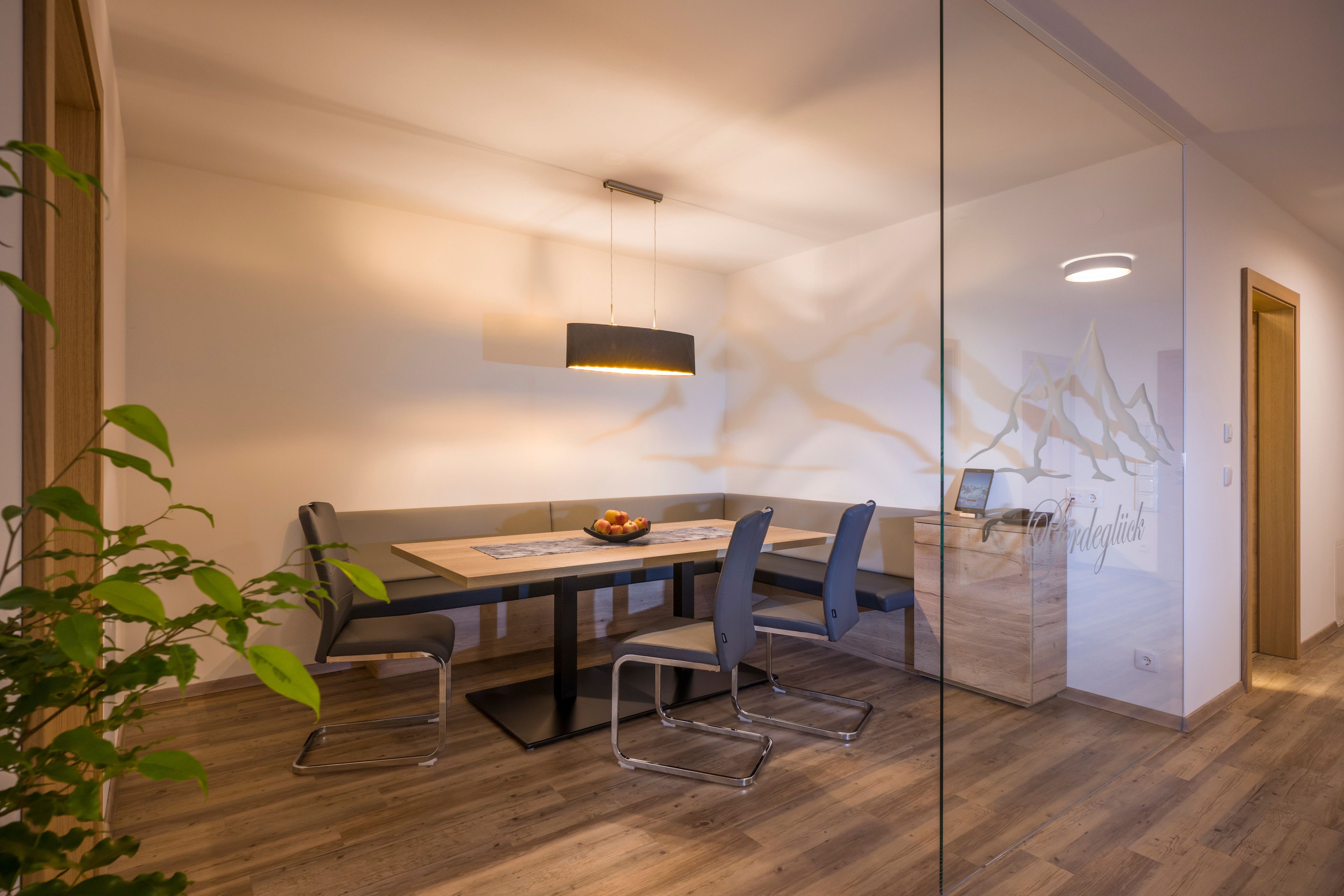 Una sala de reuniones moderna con separador de vidrio, una mesa de madera y dos sillas.