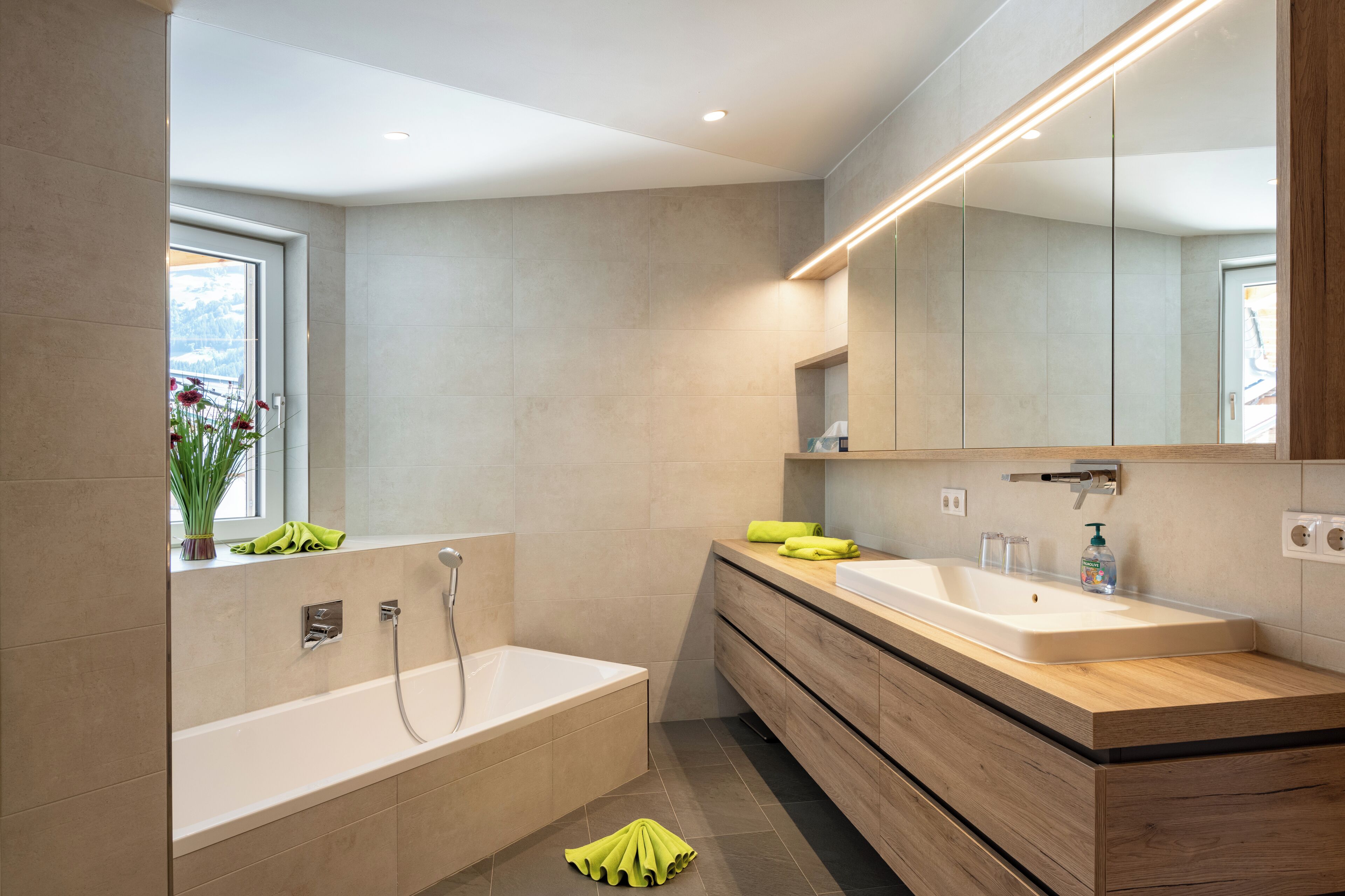A modern bathroom with a large bathtub, a double sink vanity, and a mirror above the vanity.