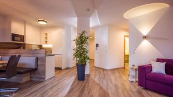 A modern living area with a dining table, sofa, and a potted plant.