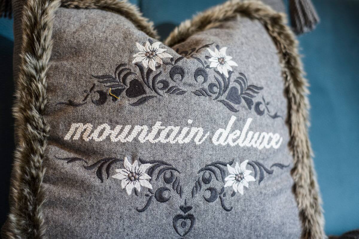 A pillow with embroidered text and floral designs.