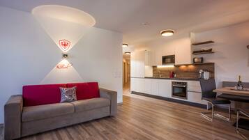 Una sala de estar moderna con un sofá rojo, una cocina con armarios blancos y un comedor con mesa y sillas.