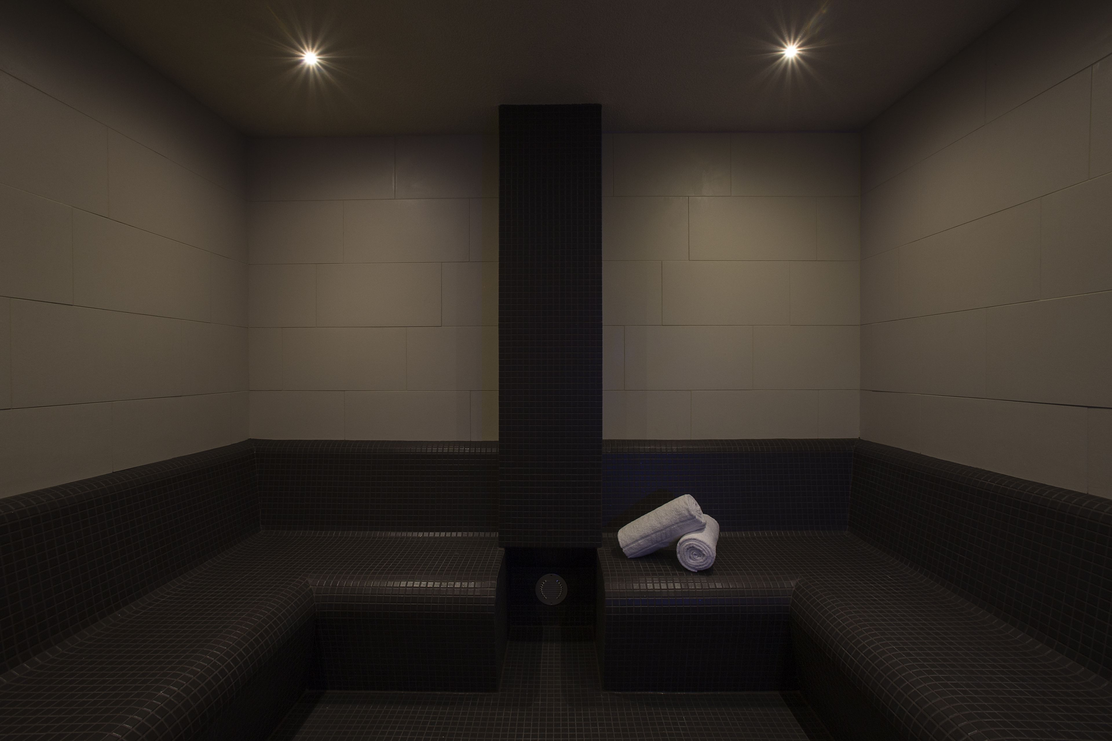 A sauna room with a central pillar, benches, and a towel on one bench.