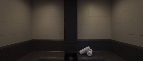 A sauna room with a central pillar, benches, and a towel on one bench.