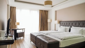 A hotel room with a large bed, a desk, a chair, and a television.