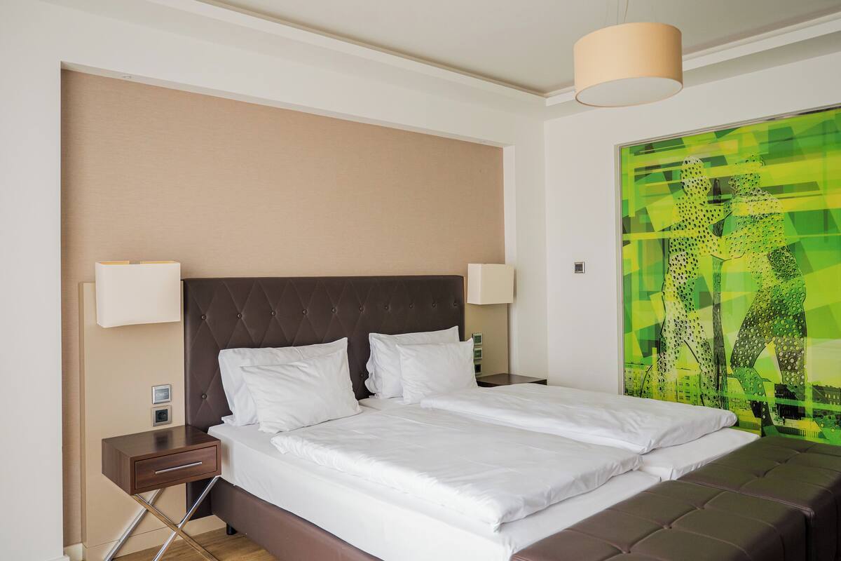 Een hotelkamer met een groot bed, twee nachtkastjes en een wandlamp.