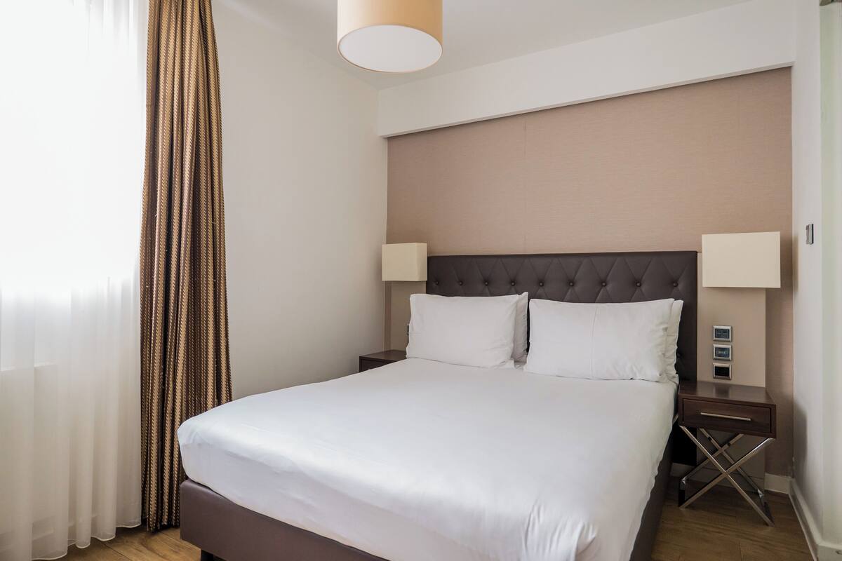 Een hotelkamer met een groot bed, twee nachtkastjes en een hoofdbord.