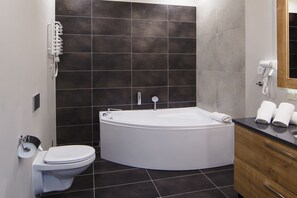 Ein modernes Badezimmer mit einer freistehenden Badewanne, einer Toilette und einem Waschtisch mit Spiegel.