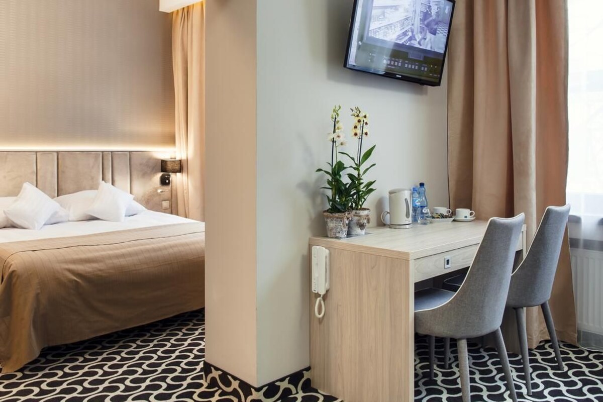 Une chambre d’hôtel comprenant un lit, un bureau avec deux chaises, une plante en pot, un téléviseur et un téléphone.