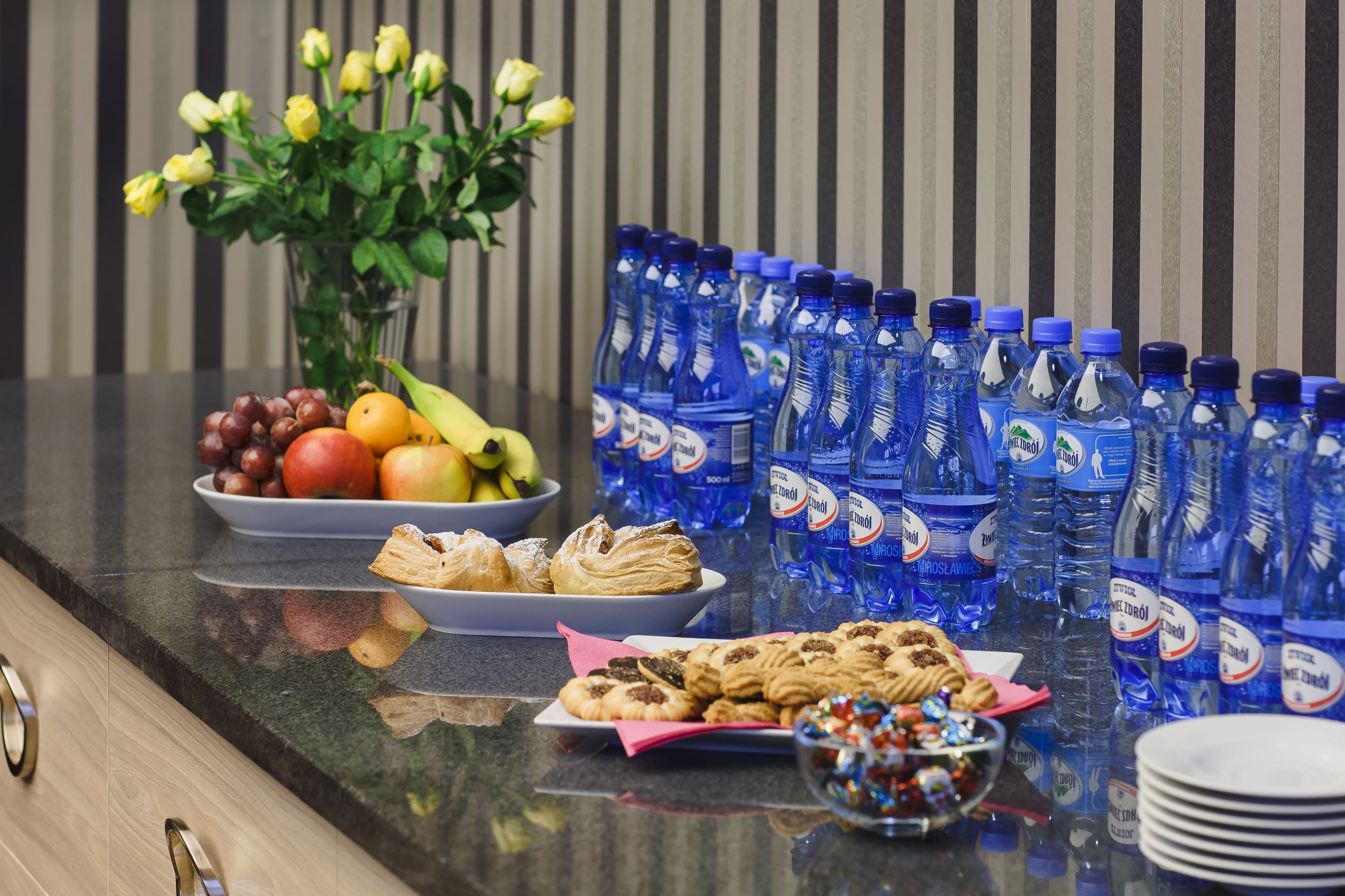 A buffet table with fruits, pastries, and bottled water.
