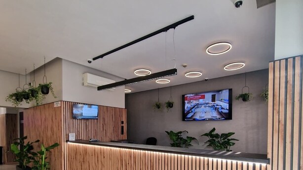 Un mostrador de recepción moderno con detalles de madera, un televisor de pantalla plana montado en la pared y un suelo de baldosas blanco y negro.