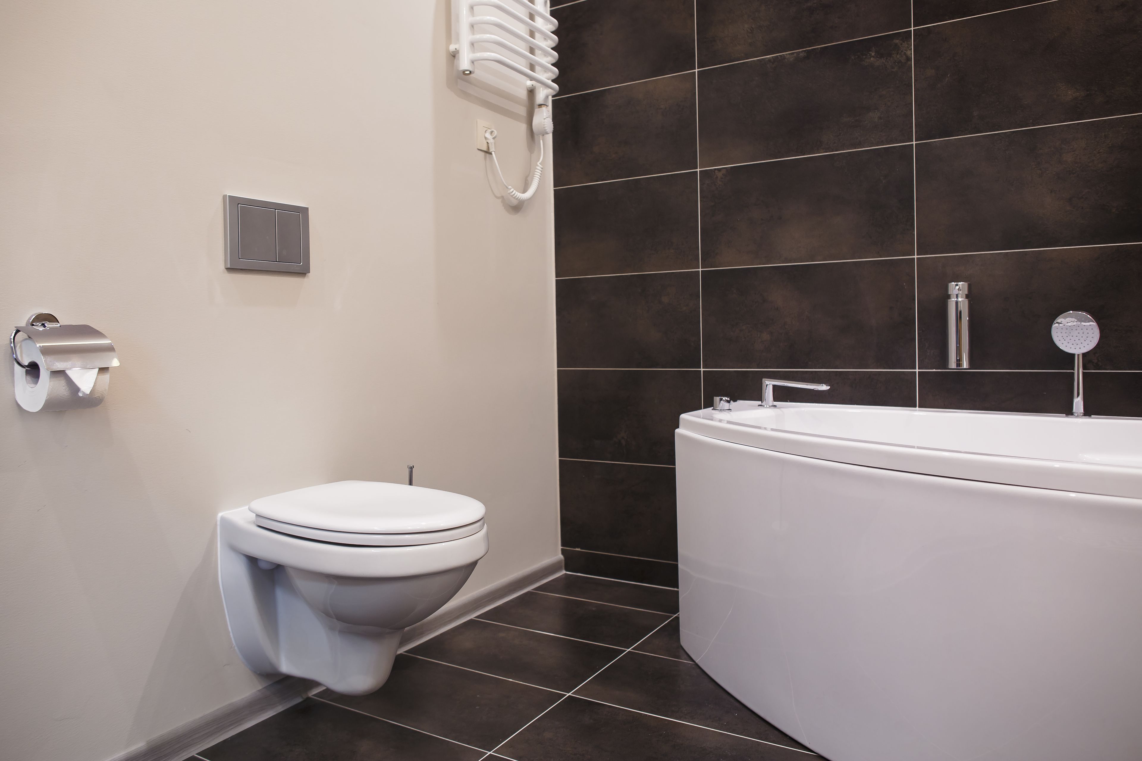 Un bagno moderno con il water, un riscaldatore a parete e una vasca da bagno.