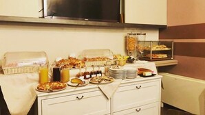 A buffet setup with various food items and beverages, including pastries, sandwiches, and fruit. - Agorà Hotel (Calamandrana)